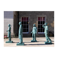 the College Statues. A bronze sculpture featuring three figures in a line, with the middle figuredominantly facing forward, while the figures on either side appear to be in a conversational pose. The sculpture is outdoors, in front of a building with large windows.